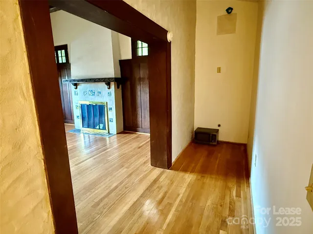 a view of a hallway with wooden floor and a bathroom