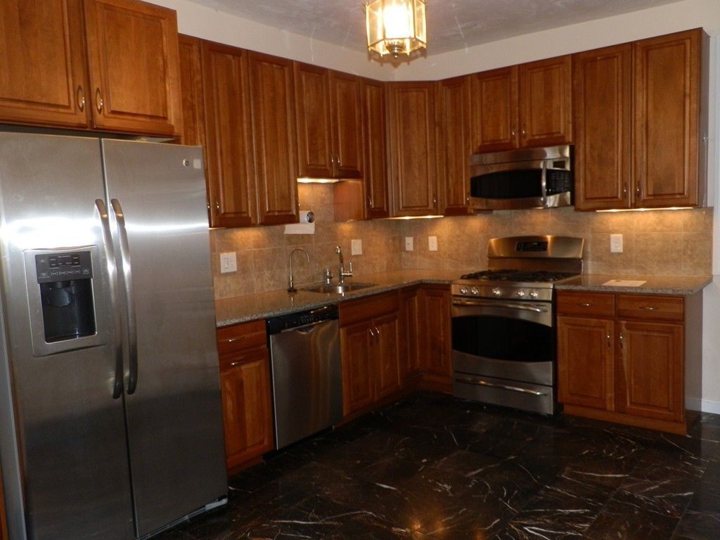 194 Auburn Street, Unit 1 Newton, MA 02466 - Photo 4 of 15 a kitchen with granite countertop stainless steel appliances and wooden cabinets