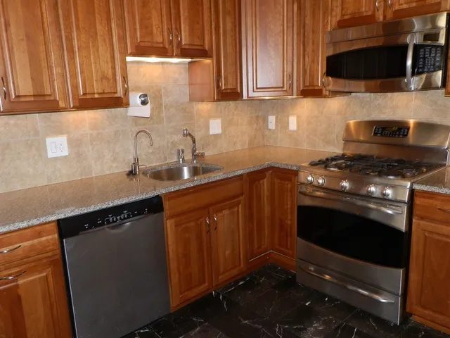 a kitchen with stainless steel appliances a stove a microwave a sink and cabinets