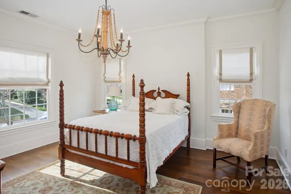 a bed room with a bed a chandelier and a chair