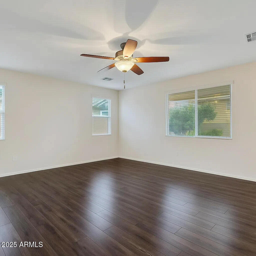 7538 West Redbird Road Peoria, AZ 85383 - Photo 10 of 24 a view of an empty room with wooden floor and a window