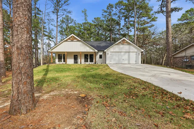 a front view of a house with a yard and large trees