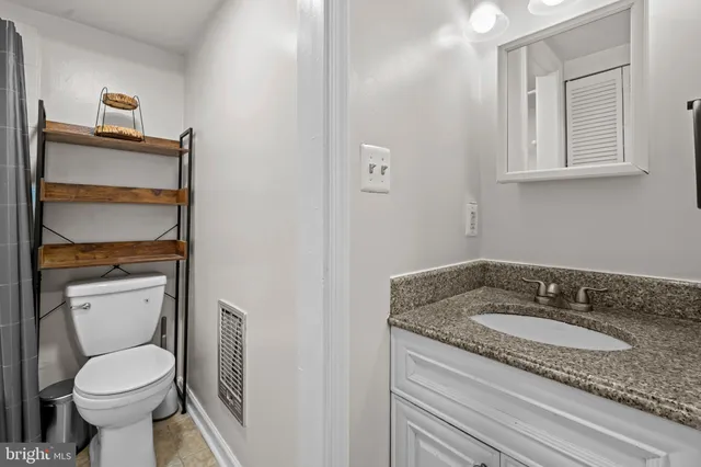 a bathroom with a granite countertop toilet sink and mirror