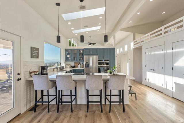 1800 Spring Oaks Drive Springville, UT 84663 - Photo 18 of 68 Kitchen with a peninsula, a kitchen bar, high vaulted ceiling, glass insert cabinets, and pendant lighting