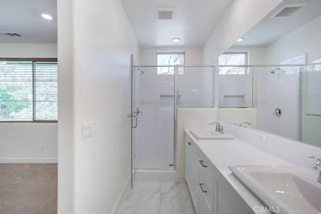 a bathroom with a granite countertop shower sink vanity and mirror