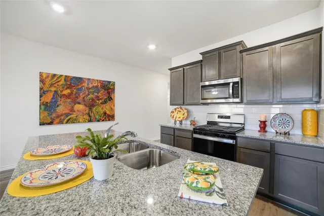 a kitchen with a stove a sink and a dining table with chairs