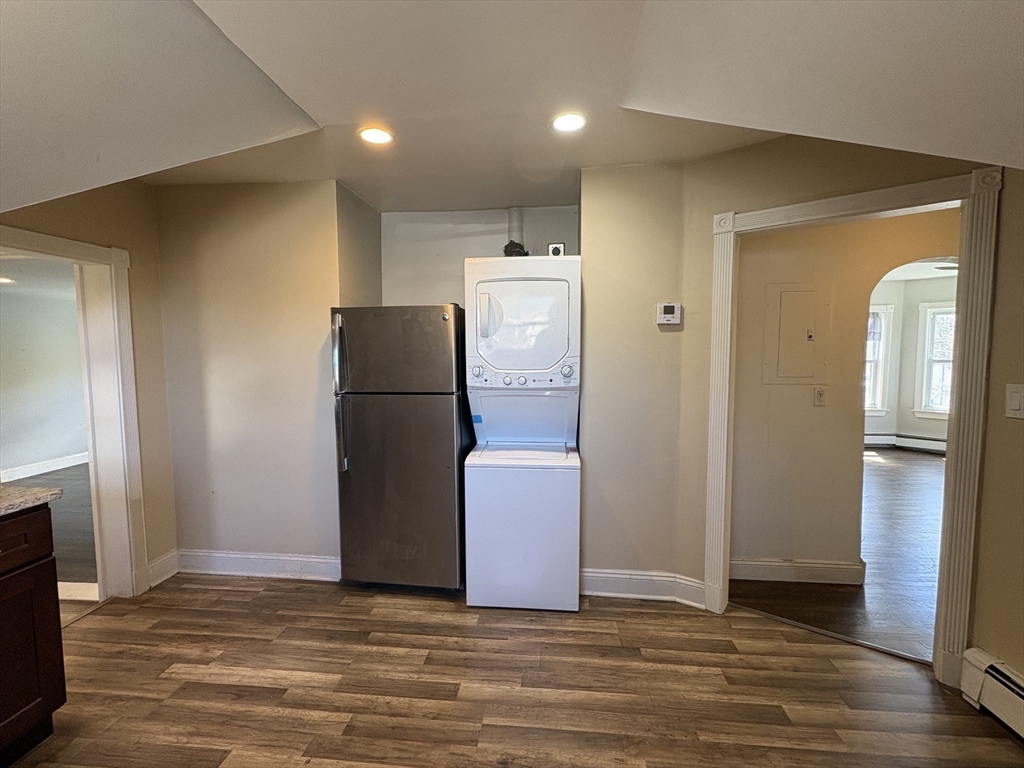 980 Washington Street, Unit 2 Stoughton, MA 02072 - Photo 3 of 10 a view of a refrigerator in kitchen and an empty room with wooden floor windows