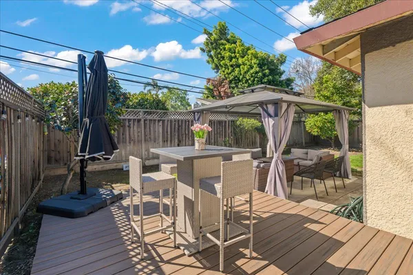a view of a patio with table and chairs with wooden floor and fence