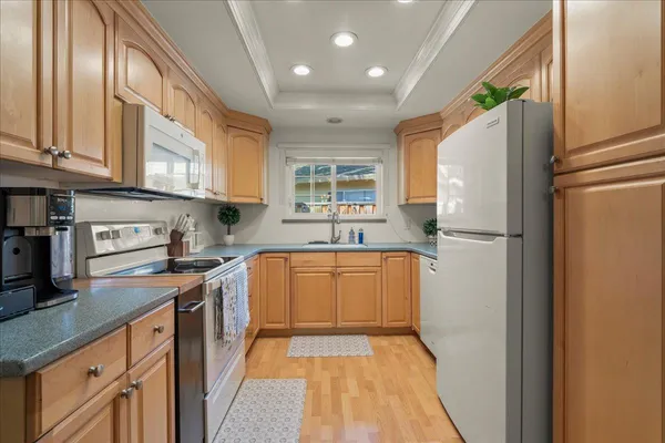 a kitchen with stainless steel appliances granite countertop a refrigerator a sink dishwasher a stove with white cabinets and wooden floor