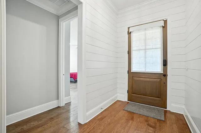 a view of an empty room with wooden floor and a kitchen