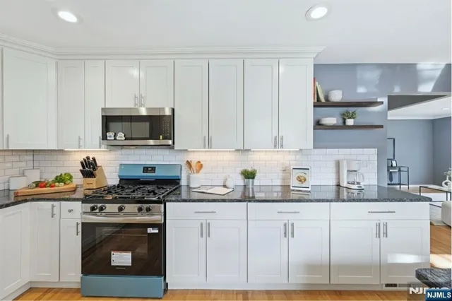a kitchen with granite countertop white cabinets and stainless steel appliances