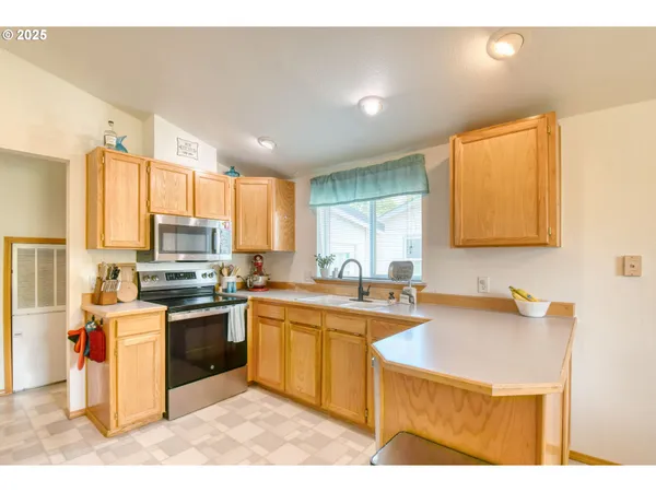 a kitchen with stainless steel appliances granite countertop a sink stove refrigerator and cabinets