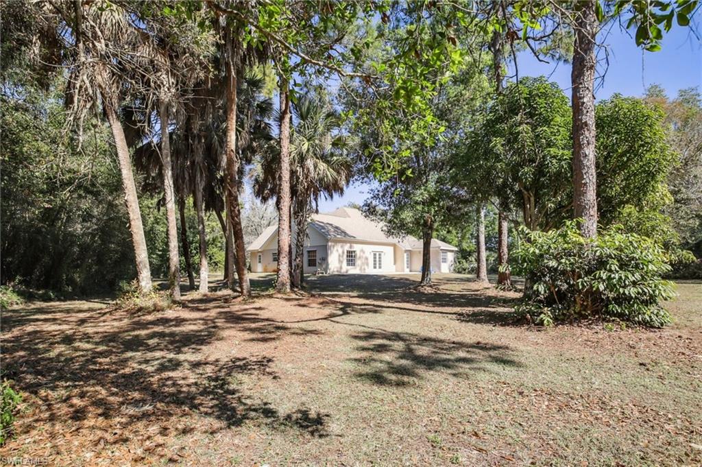 5348 Cypress Lane Naples, FL 34113 - Photo 28 of 28 a backyard of a house with large trees and outdoor seating