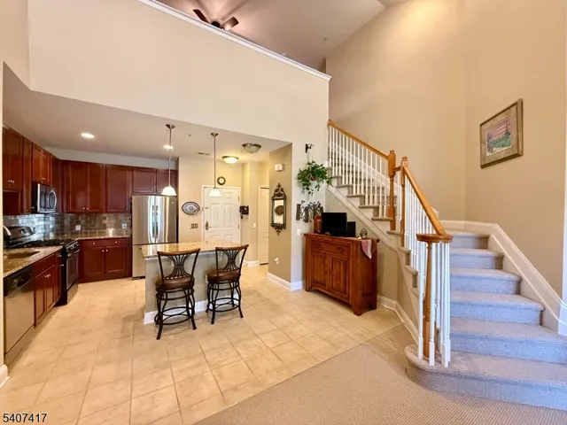 a dining hall with couches chairs and kitchen view with wooden floor