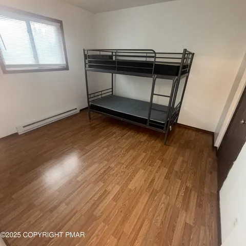 an empty room with wooden floor fireplace and windows
