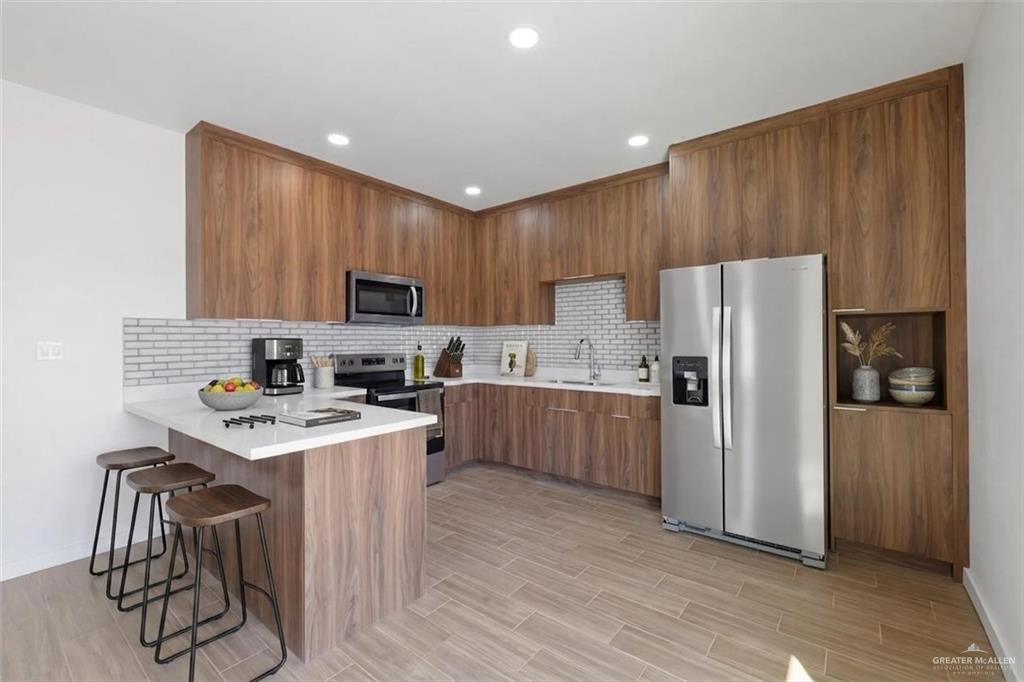 2902 Gabriel Street, Unit 2 Mission, TX 78574 - Photo 6 of 15 a kitchen with a refrigerator a stove top oven a sink and dishwasher with wooden floor