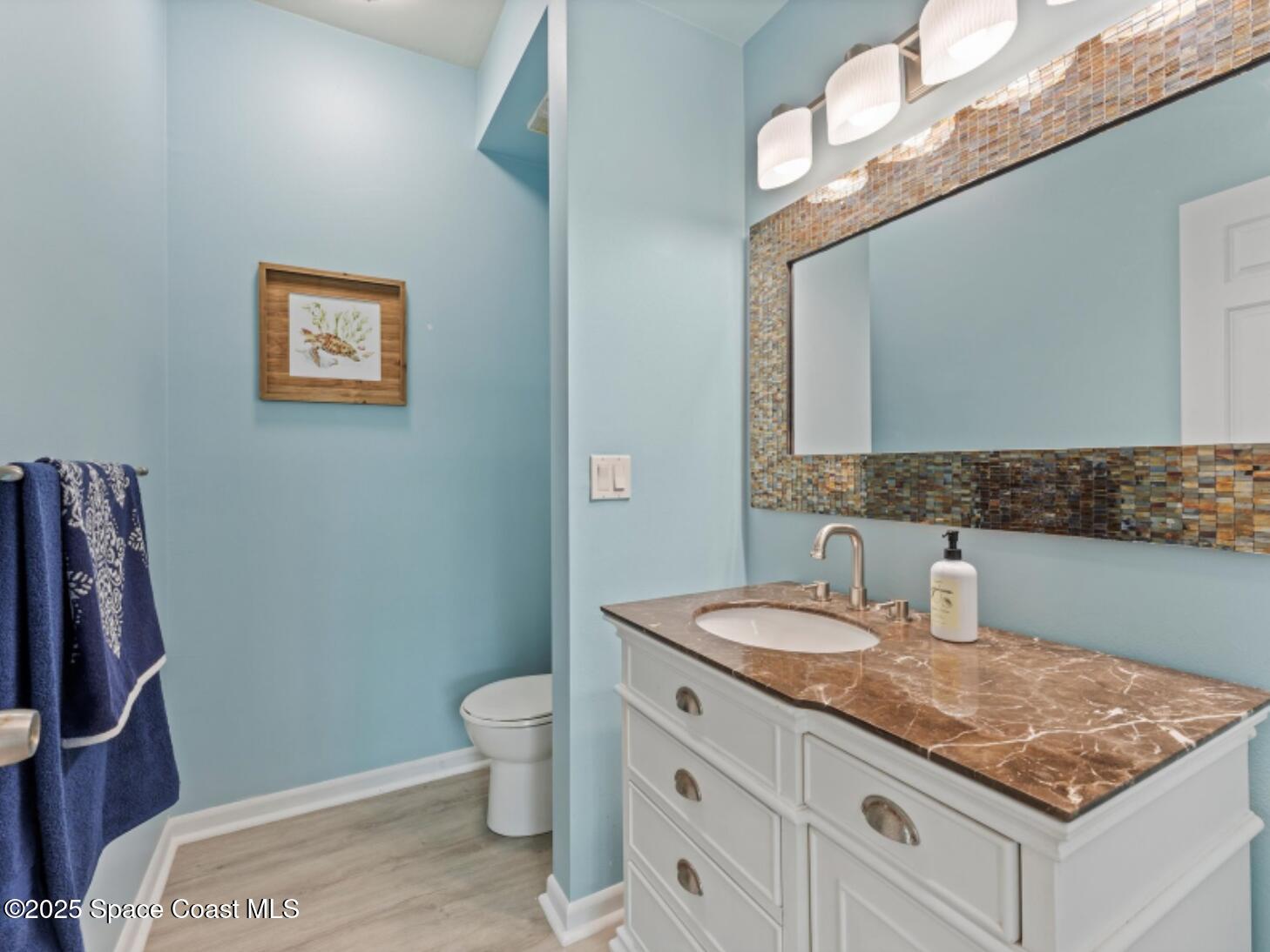 3037 S Highway, Unit 2C Melbourne Beach, FL 32951 - Photo 28 of 48 a bathroom with a granite countertop sink a toilet and a mirror