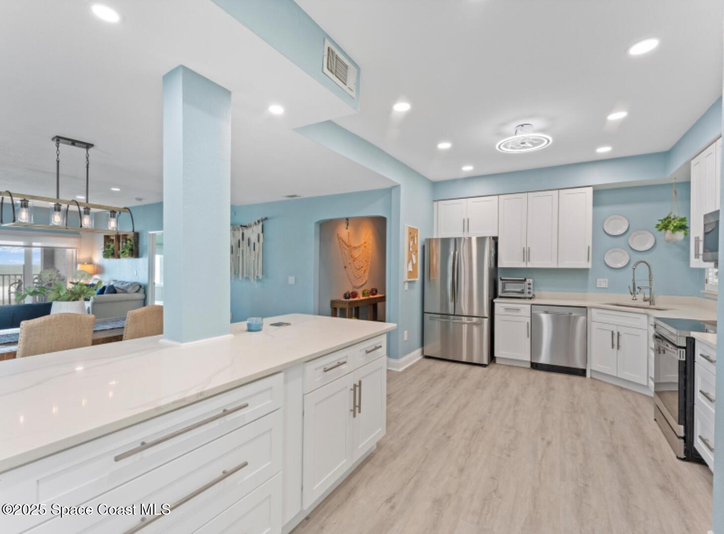 3037 S Highway, Unit 2C Melbourne Beach, FL 32951 - Photo 4 of 48 a large white kitchen with a refrigerator a sink dishwasher and white cabinets next to a window