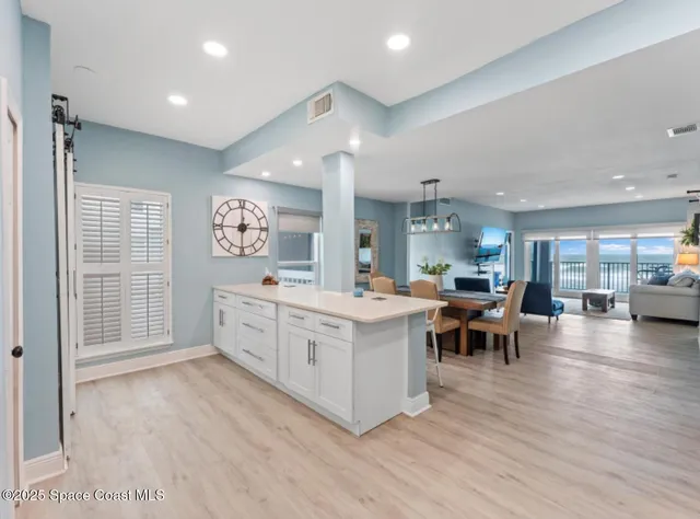 a room with kitchen island dining table wooden floor and kitchen view