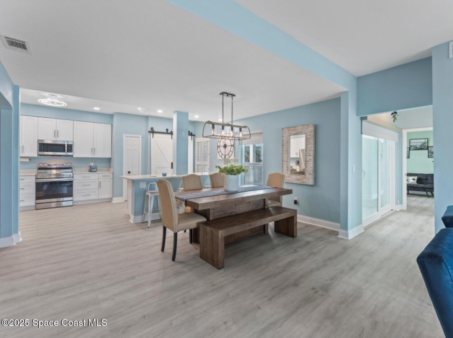 3037 S Highway, Unit 2C Melbourne Beach, FL 32951 - Photo 8 of 48 a room with kitchen island dining table wooden floor and kitchen view
