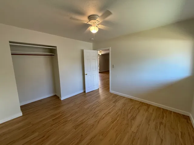 an empty room with wooden floor and a ceiling fan