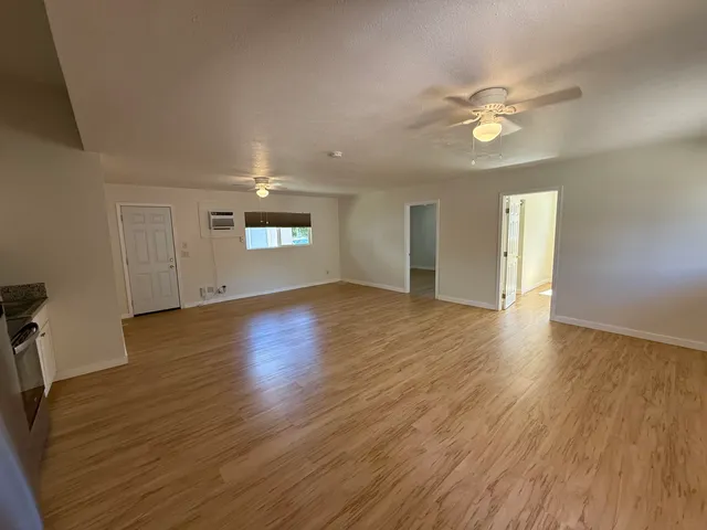 a view of empty room with wooden floor and fan
