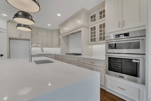 a large kitchen with a sink and dishwasher a stove top oven with wooden floor