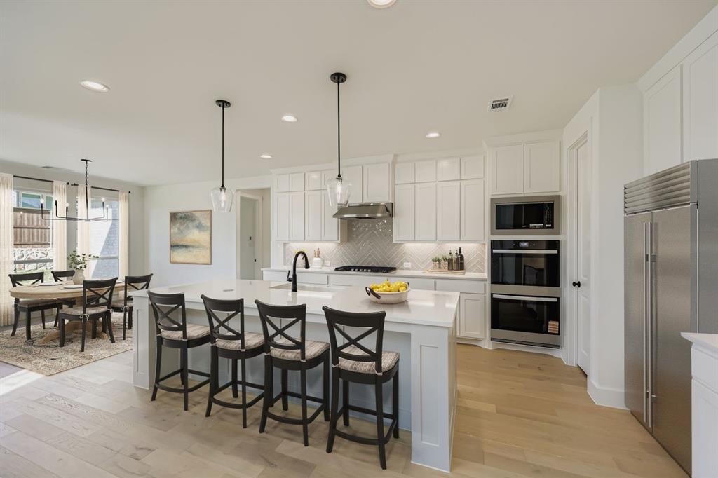 1841 Pk Vista Way Midlothian, TX 76065 - Photo 7 of 28 a kitchen with kitchen island a dining table chairs stainless steel appliances and cabinets