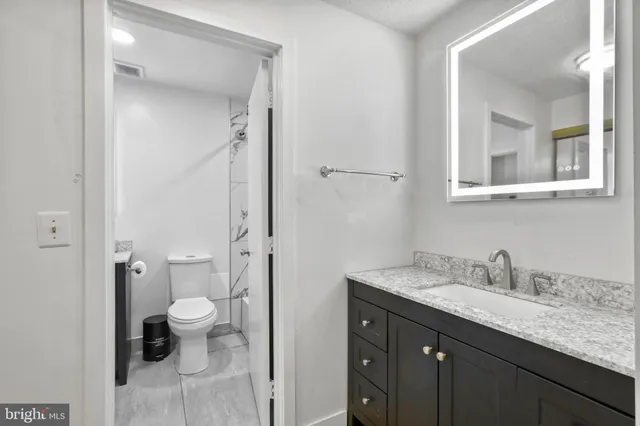 a bathroom with a granite countertop sink toilet and shower