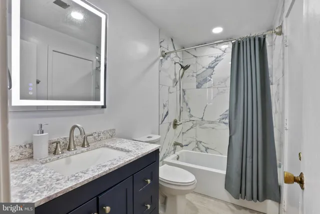 a bathroom with a granite countertop sink toilet and shower