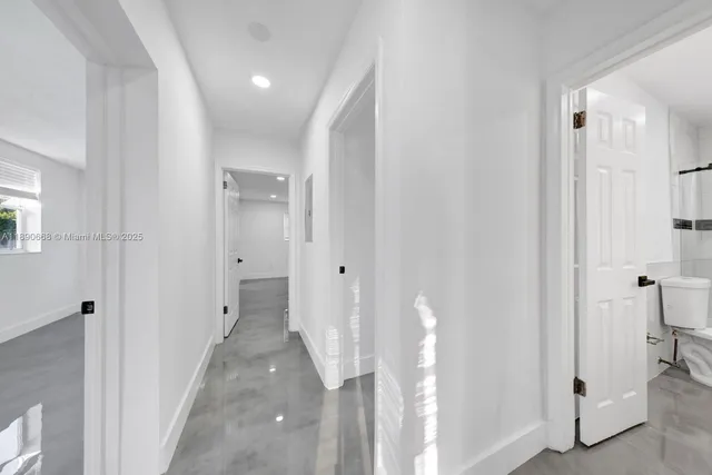 an empty room with windows and refrigerator