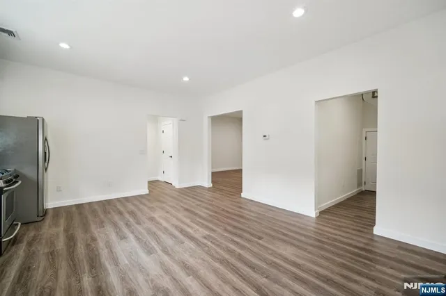 a view of an empty room with wooden floor and a fireplace