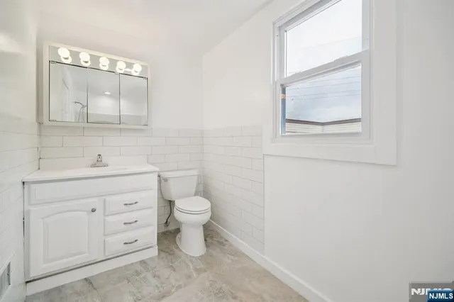 a bathroom with a toilet a sink a vanity and mirror