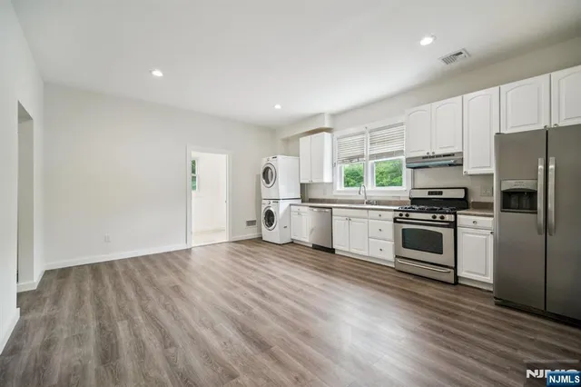 a kitchen with granite countertop a refrigerator and a stove top oven