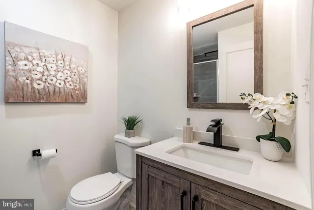 a bathroom with a granite countertop sink a toilet and mirror
