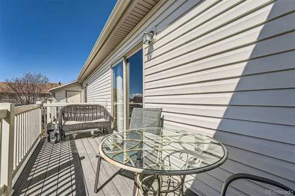 a balcony with table and chairs with wooden floor and fence