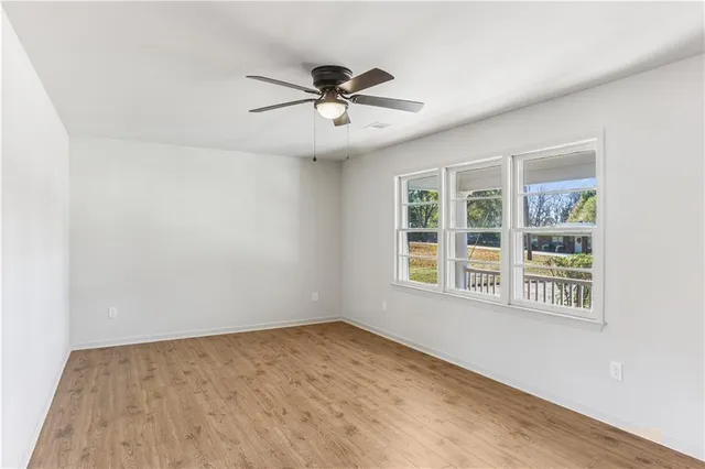 an empty room with windows and fan