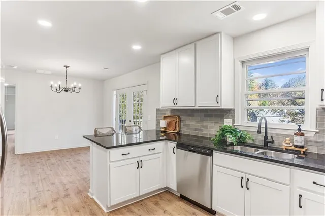 a kitchen with granite countertop white cabinets white appliances a sink and a window