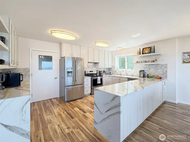 a large kitchen with kitchen island a large counter top stainless steel appliances and cabinets