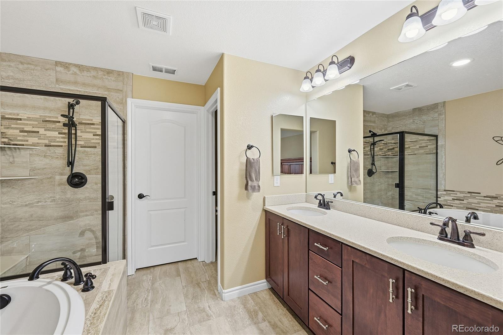 9500 Pendio Court Highlands Ranch, CO 80126 - Photo 10 of 15 a spacious bathroom with a double vanity sink mirror double and shower