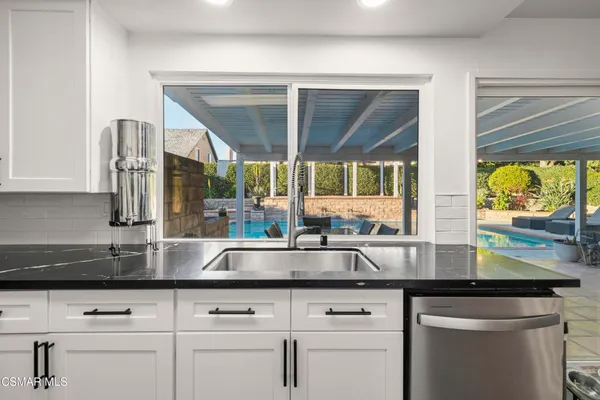 a kitchen with stainless steel appliances granite countertop white cabinets and a large window