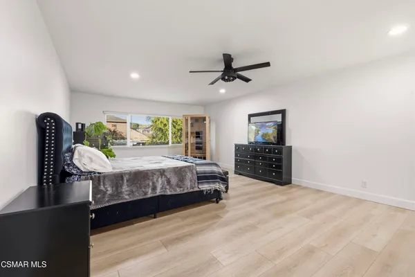 a spacious bedroom with a bed a dresser and a bookshelf