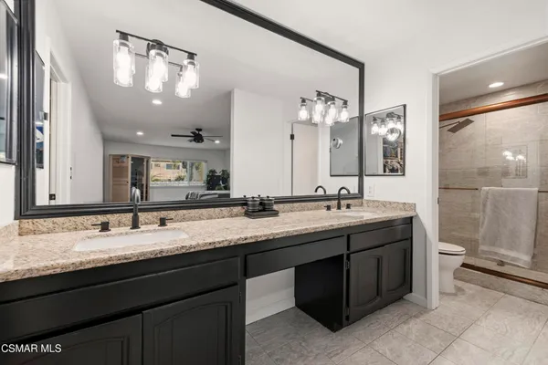 a bathroom with a granite countertop sink a toilet and a mirror