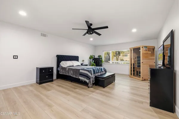 a spacious bedroom with a bed and wooden floor