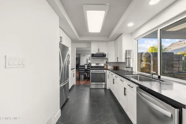 a large kitchen with granite countertop a large window and stainless steel appliances