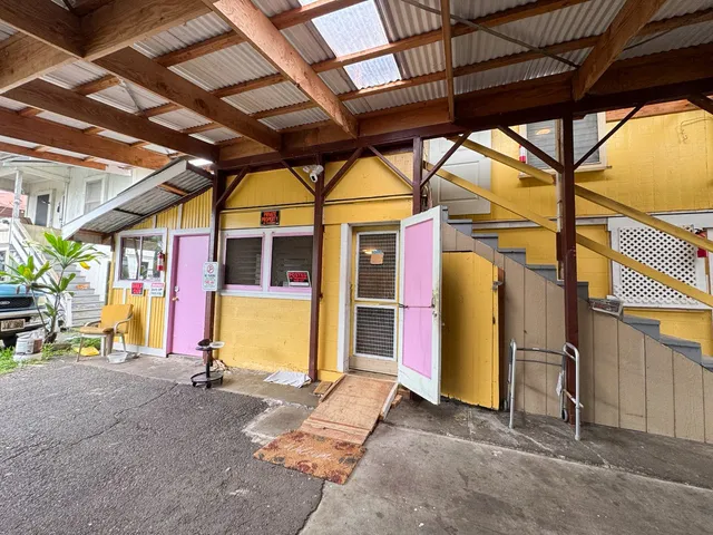 a view of a garage with wooden table and chairs under an umbrella