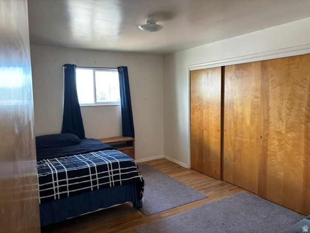 237 North 500 West Vernal, UT 84078 - Photo 5 of 11 Bedroom featuring wood-finish flooring, a window with natural light, and a built-in closet with double sliding doors