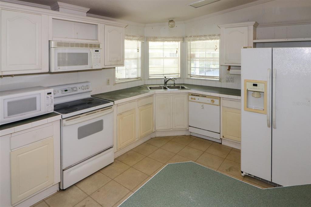 29200 South Jones Loop Road, Unit 205 Punta Gorda, FL 33950 - Photo 5 of 25 a kitchen with white cabinets and white appliances