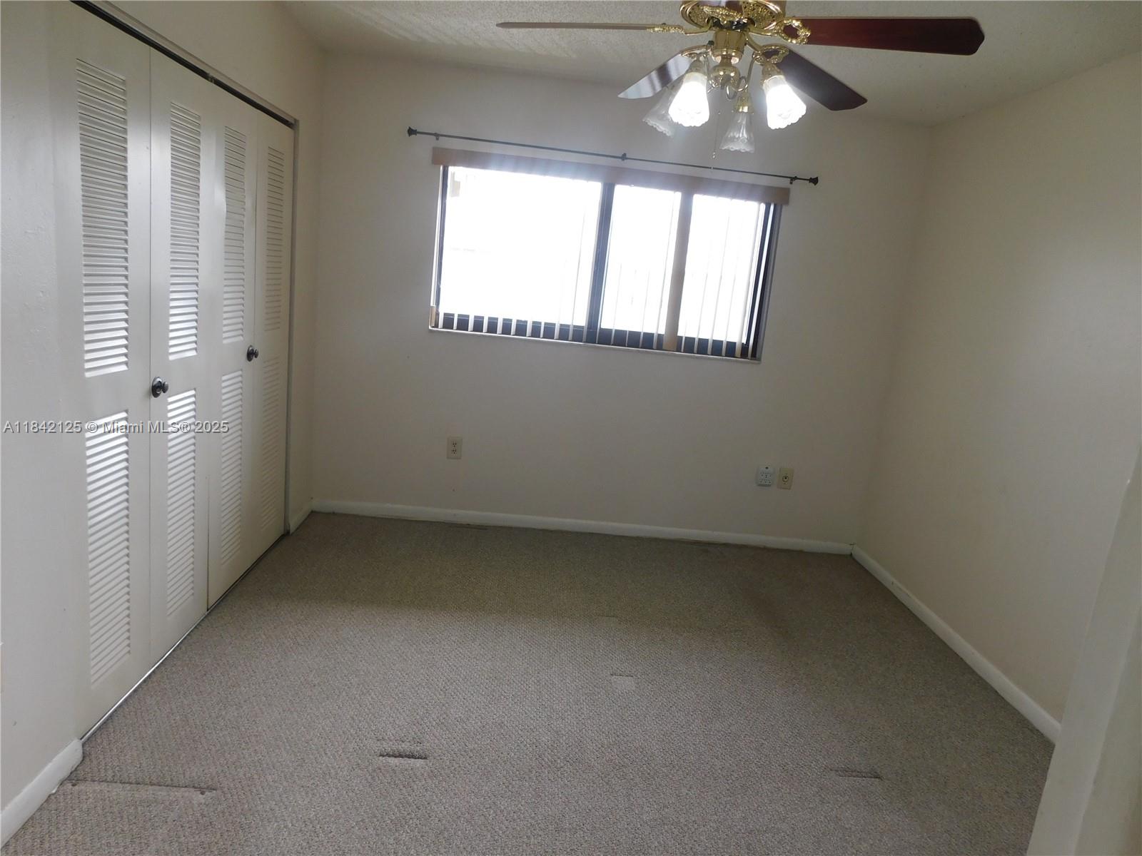 1121 Southwest 105th Avenue, Unit 322 Miami, FL 33174 - Photo 14 of 19 an empty room with a chandelier fan and windows