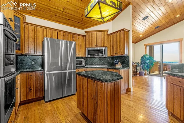 a kitchen with stainless steel appliances granite countertop a refrigerator a stove and a sink with wooden floor